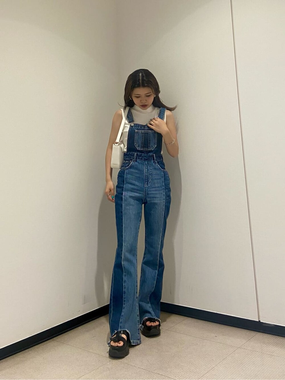 ホワイト系のタンクトップ、ブルー系のサロペット/オーバーオール、ブラック系のサンダルを着用したレディースの夏コーディネートの1枚目の写真