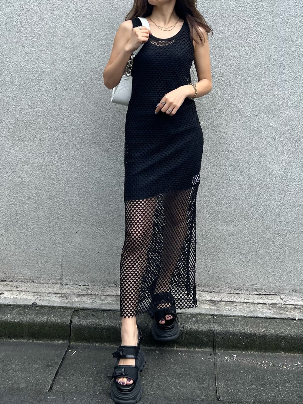 ブラック系のワンピース、ブラック系のサンダル、ホワイト系のハンドバッグを着用したレディースの夏コーディネートの1枚目の写真