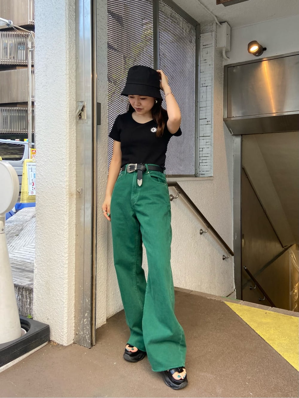 ブラック系のTシャツ/カットソー、グリーン系のデニムパンツ、ブラック系のサンダルを着用したレディースの春コーディネートの1枚目の写真