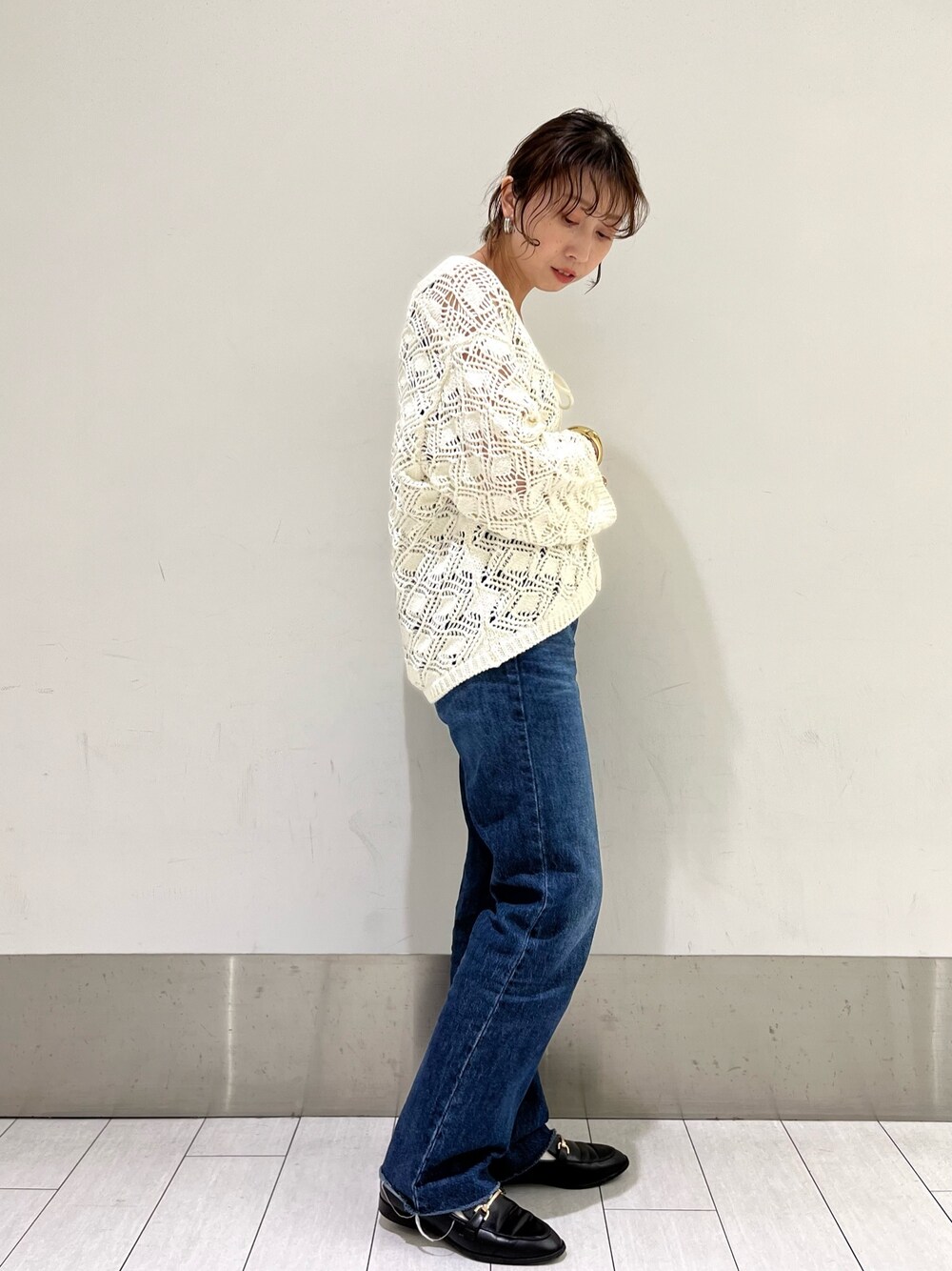 ブルー系のデニムパンツ、ホワイト系のカーディガン/ボレロ、ブラック系のローファーを着用したレディースの春コーディネートの2枚目の写真