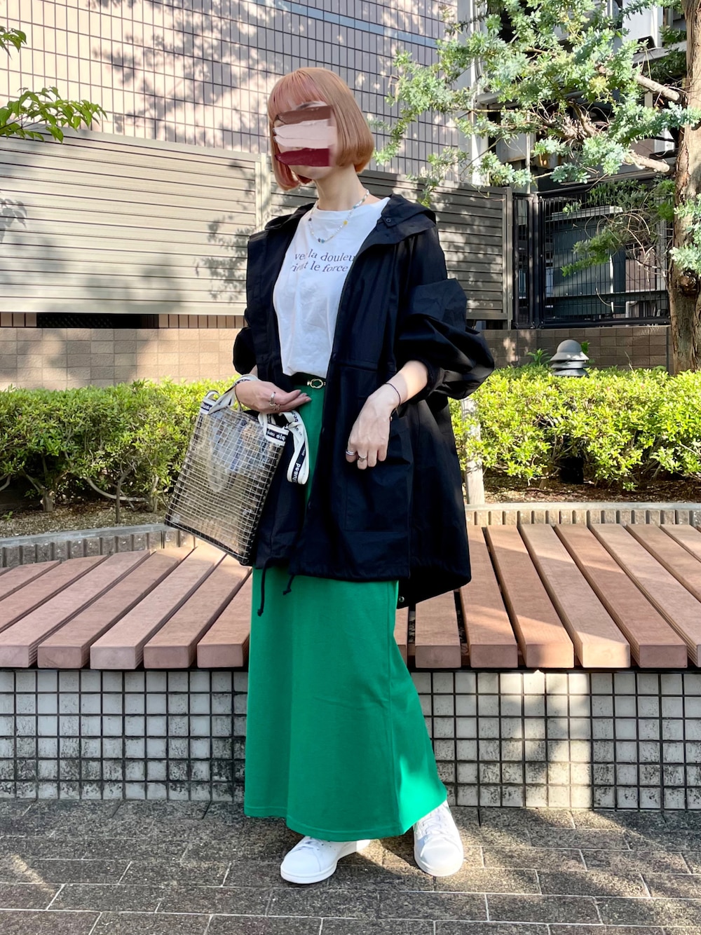 ブラック系のマウンテンパーカー、ホワイト系のTシャツ/カットソー、グリーン系のスカートを着用したレディースの春コーディネートの1枚目の写真