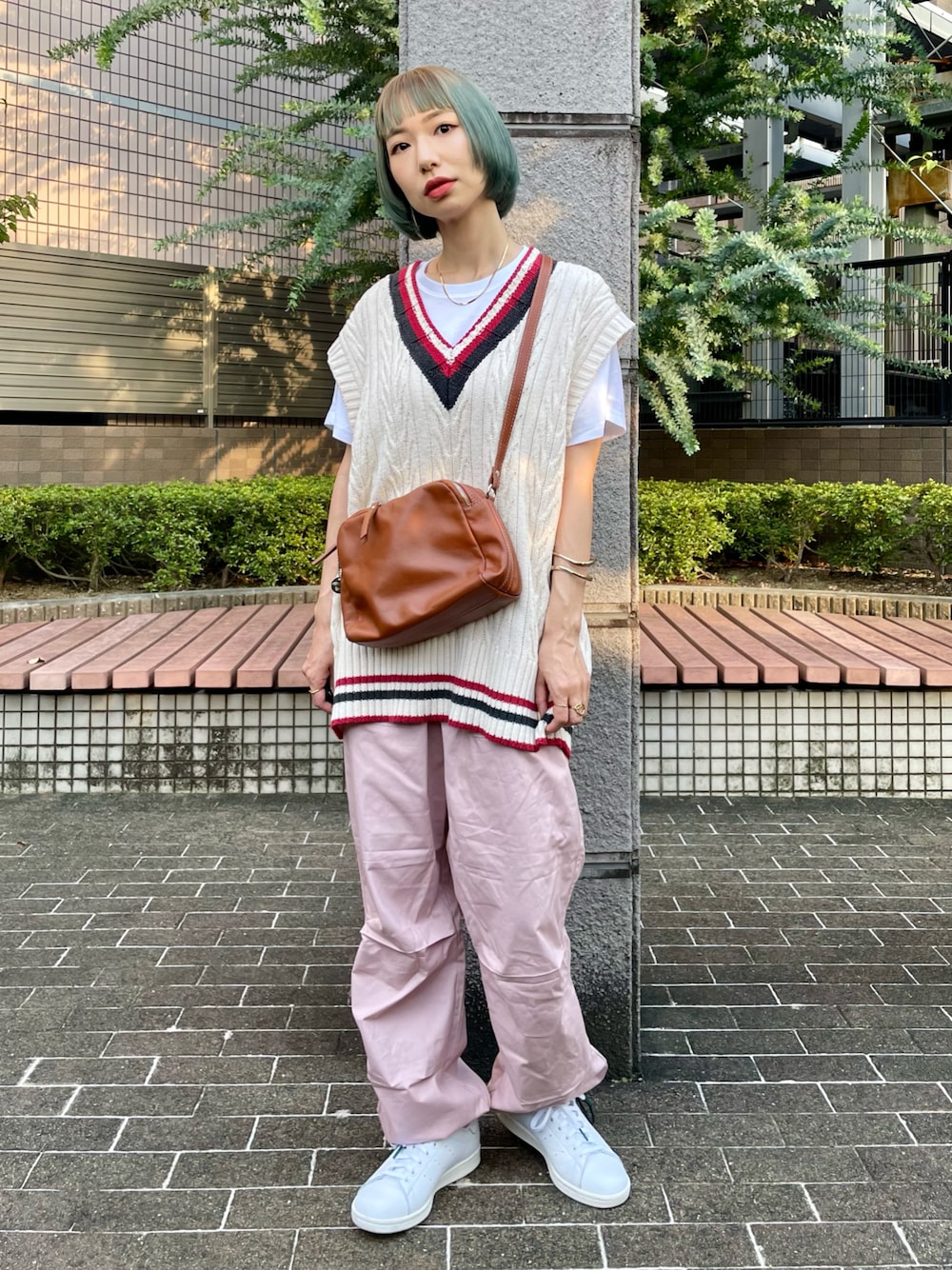 ピンク系のカーゴパンツ、ホワイト系のベスト、ブラウン系のショルダーバッグを着用したレディースの秋コーディネートの1枚目の写真