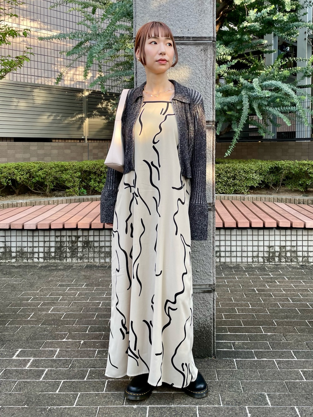 ブラック系のニット/セーター、ホワイト系のワンピース、ブラック系のブーツを着用したレディースの秋コーディネートの1枚目の写真