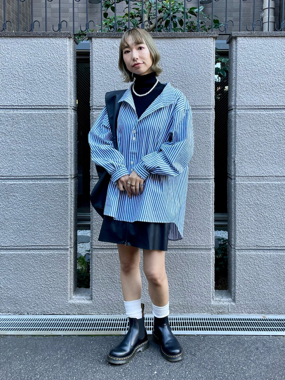 グリーン系のシャツ/ブラウス、ブラック系のニット/セーター、ブラック系のスカートを着用したレディースの秋コーディネートの1枚目の写真