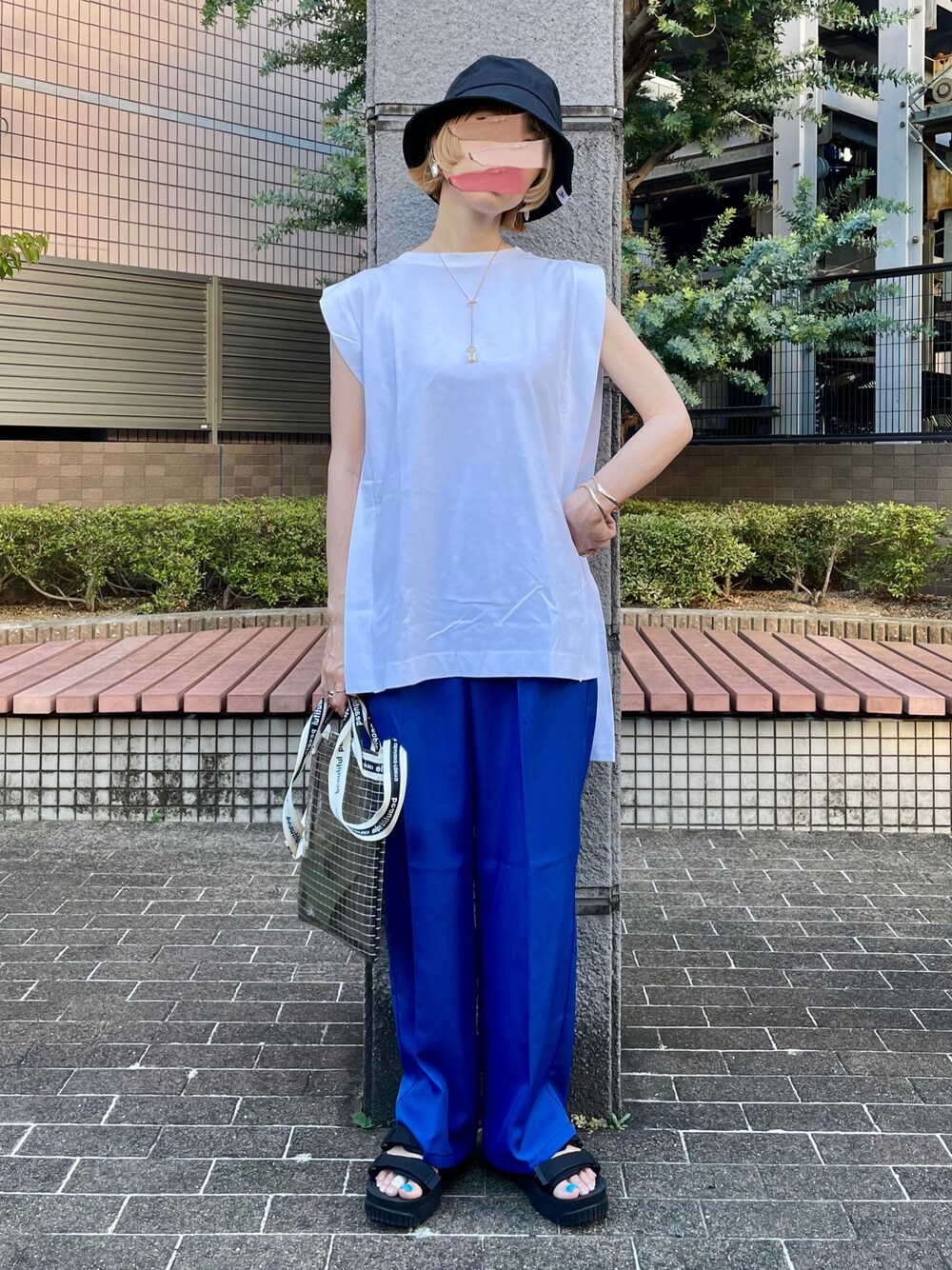 ブルー系のスラックス、ホワイト系のTシャツ/カットソー、ブラック系のサンダルを着用したレディースの夏コーディネートの1枚目の写真