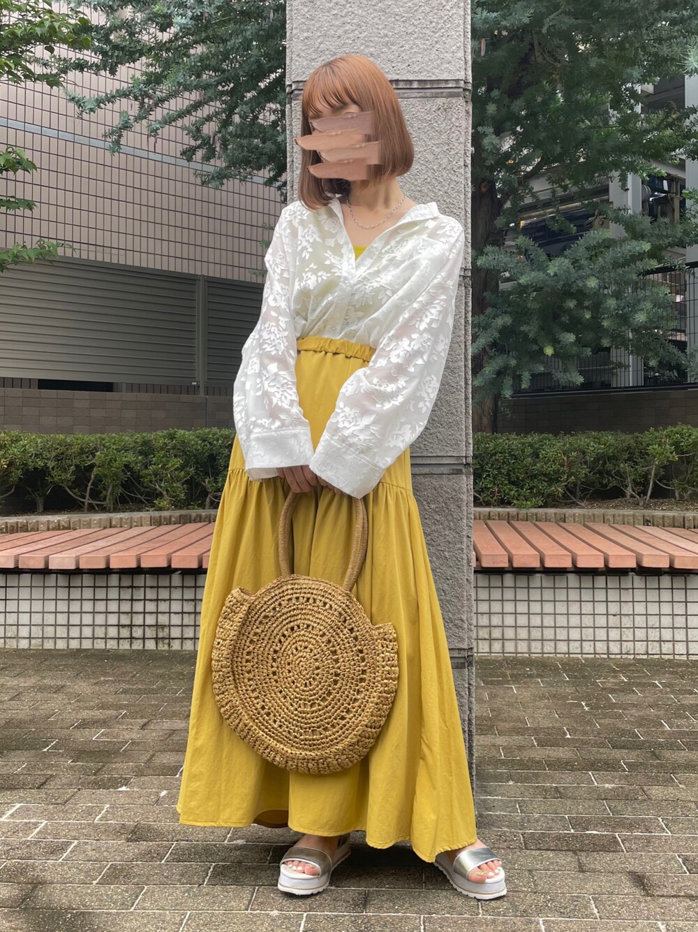 ベージュ系のかごバッグ、イエロー系のスカート、シルバー系のサンダルを着用したレディースの夏コーディネートの1枚目の写真