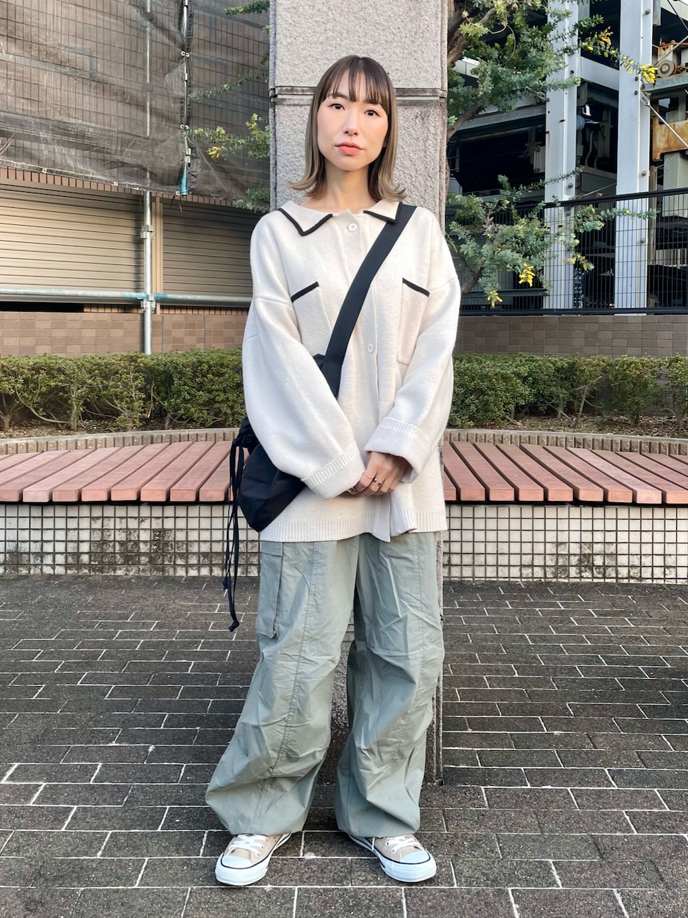 グリーン系のカーゴパンツ、ホワイト系のカーディガン/ボレロ、ベージュ系のスニーカーを着用したレディースの春コーディネートの1枚目の写真