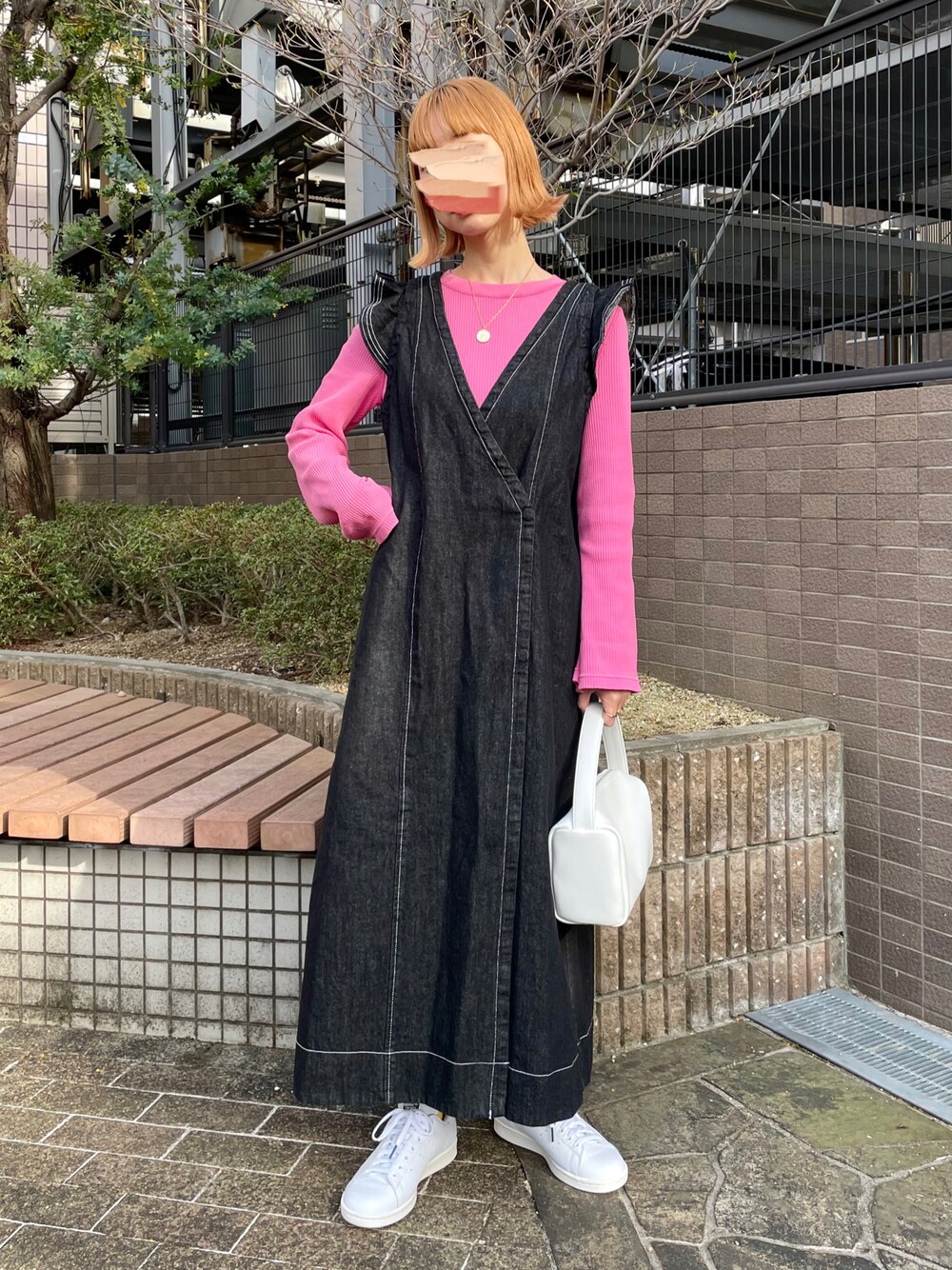 ブラック系のワンピース、ピンク系のTシャツ/カットソー、ホワイト系のハンドバッグを着用したレディースの春コーディネートの1枚目の写真