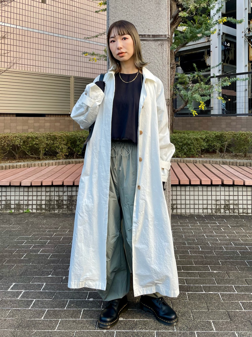 ブラック系のTシャツ/カットソー、ホワイト系のステンカラーコート、グリーン系のカーゴパンツを着用したレディースの冬コーディネートの1枚目の写真