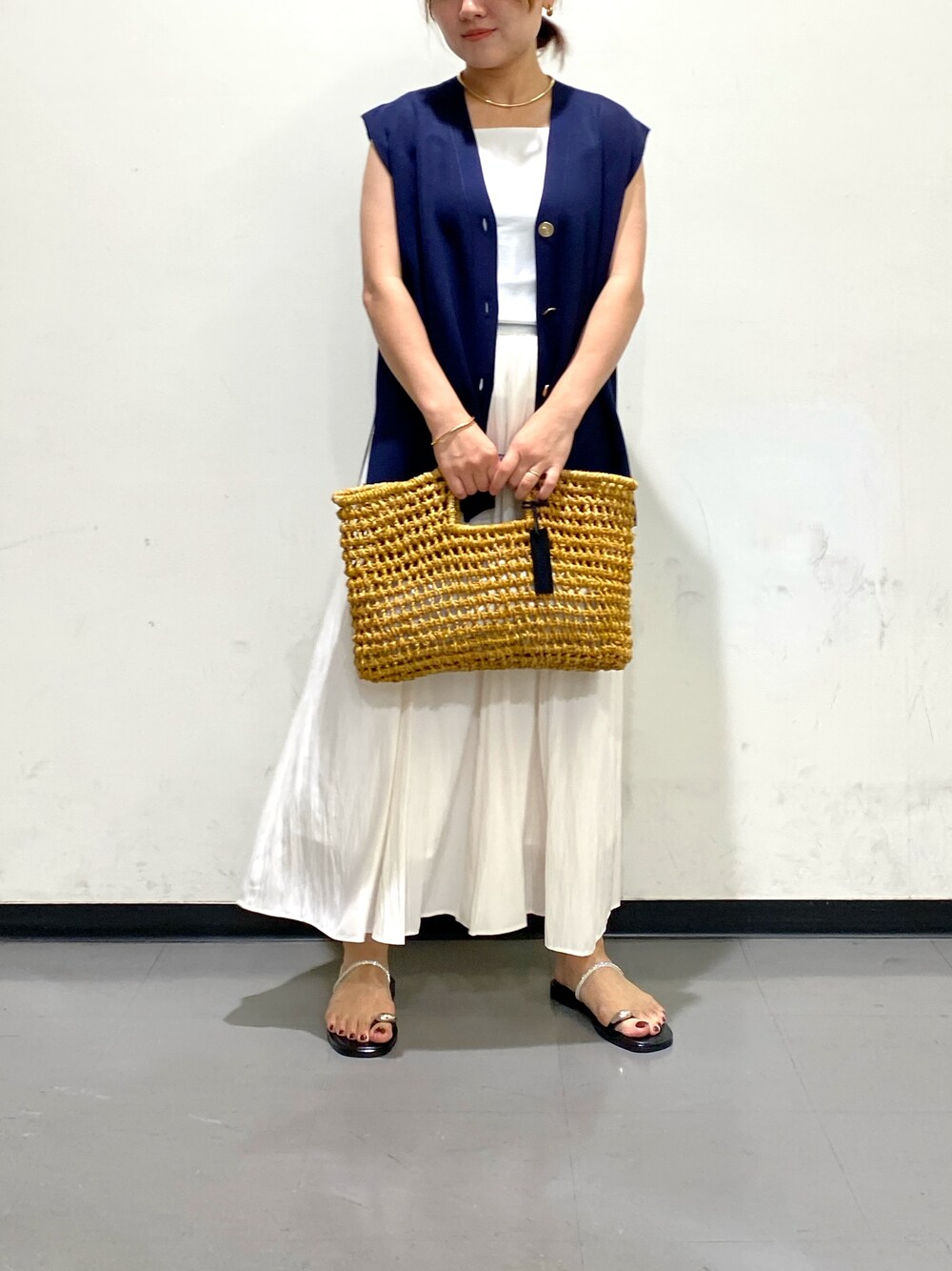 ベージュ系のかごバッグ、ブラウン系のサンダル、ブルー系のベストを着用したレディースの夏コーディネートの1枚目の写真