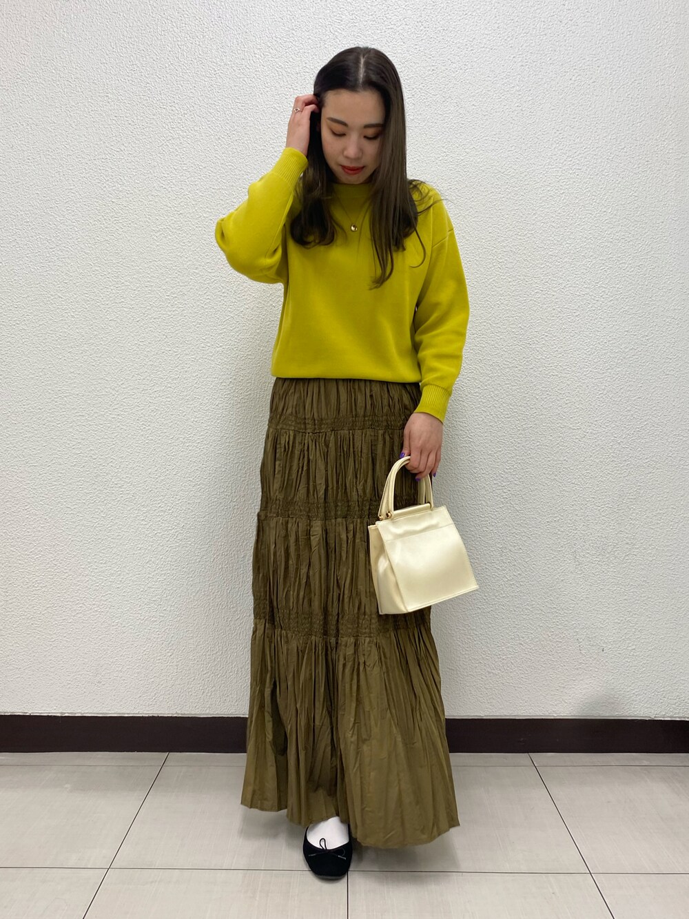 ホワイト系のハンドバッグ、イエロー系のニット/セーター、ブラウン系のスカートを着用したレディースの冬コーディネートの1枚目の写真