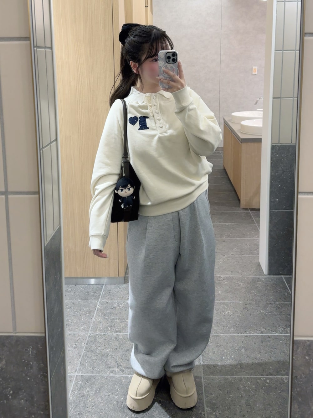 ホワイト系のポロシャツ、グレー系のスウェットパンツ、その他のショルダーバッグを着用したレディースの冬コーディネートの1枚目の写真