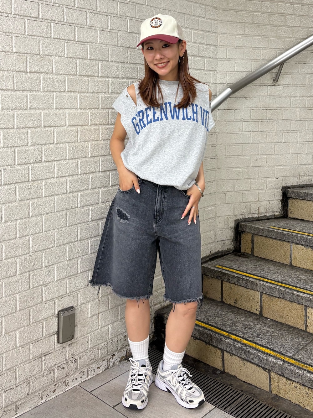 グレー系のタンクトップ、ブラック系のデニムパンツ、ホワイト系のキャップを着用したレディースの夏コーディネートの1枚目の写真