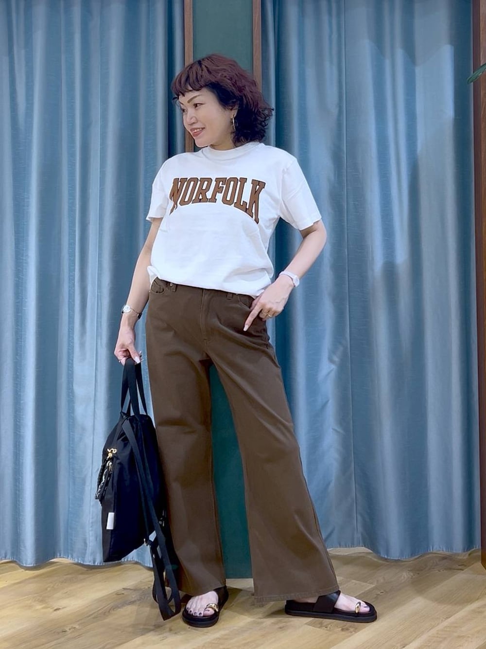 ブラック系のサンダル、ブラック系のバックパック/リュック、ホワイト系のTシャツ/カットソーを着用したレディースの夏コーディネートの1枚目の写真