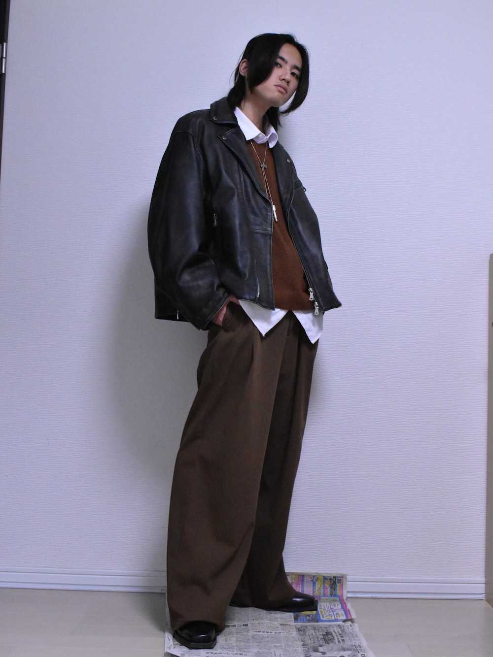 ブラウン系のスラックス、ブラック系のライダースジャケット、ブラウン系のニット/セーターを着用したメンズの冬コーディネートの1枚目の写真