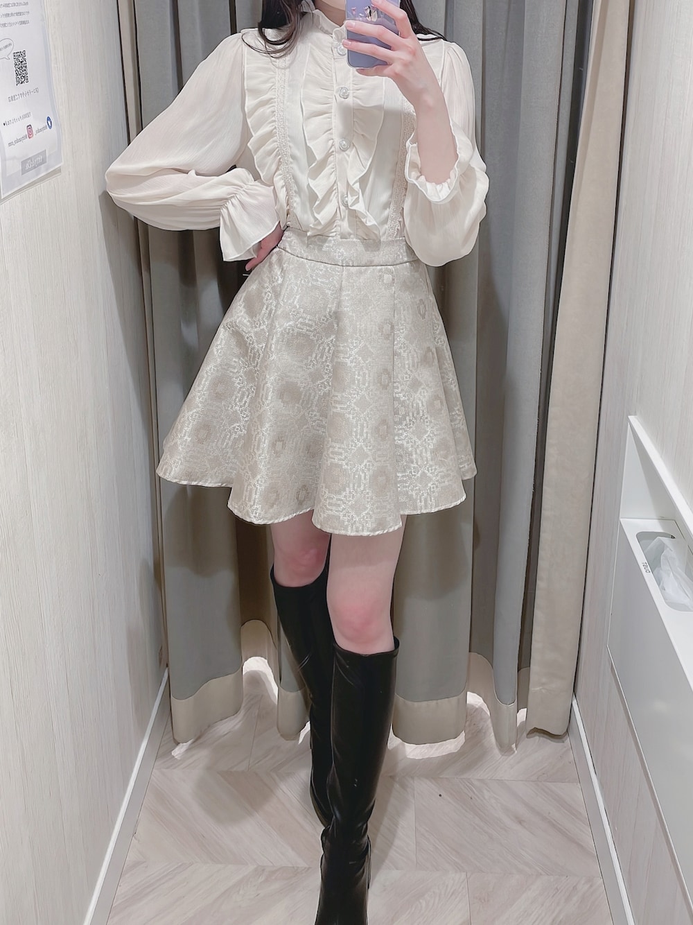 ベージュ系のシャツ/ブラウス、ベージュ系のスカート、ブラック系のブーツを着用したレディースの冬コーディネートの1枚目の写真