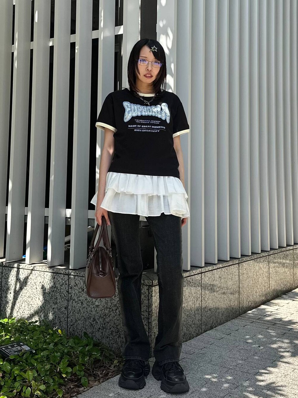 ブラック系のスニーカー、ブラック系のデニムパンツ、ブラウン系のショルダーバッグを着用したレディースの夏コーディネートの1枚目の写真