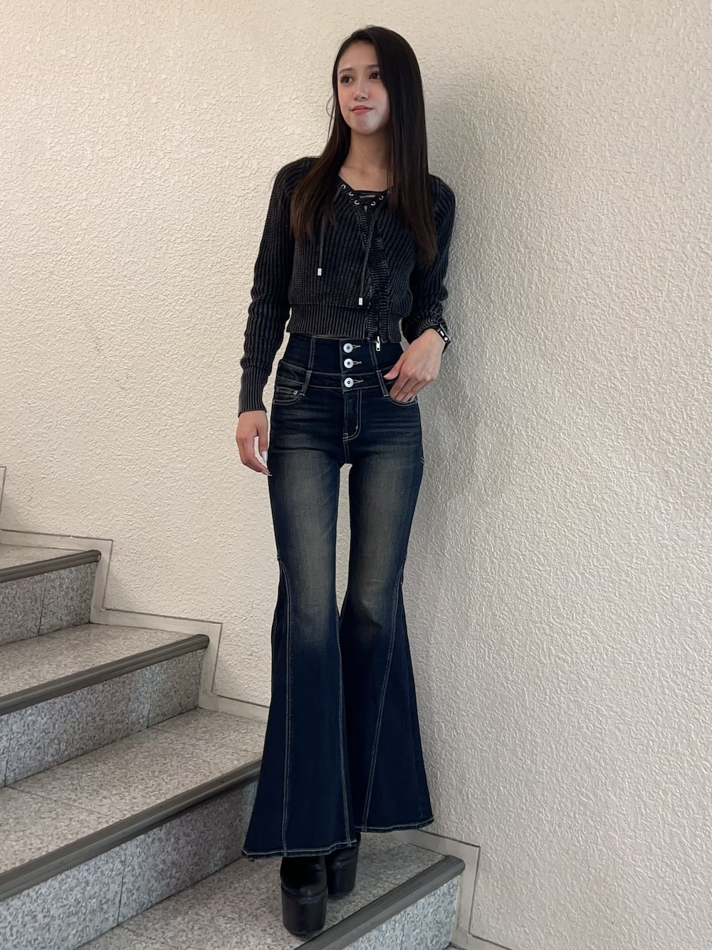 ブルー系のデニムパンツ、ブラック系のニット/セーター、ブラック系のブーツを着用したレディースの秋コーディネートの1枚目の写真