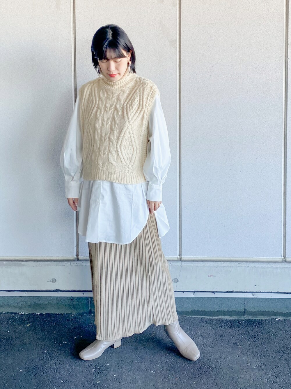 ベージュ系のベスト、ホワイト系のシャツ/ブラウス、ベージュ系のスカートを着用したレディースの秋コーディネートの1枚目の写真