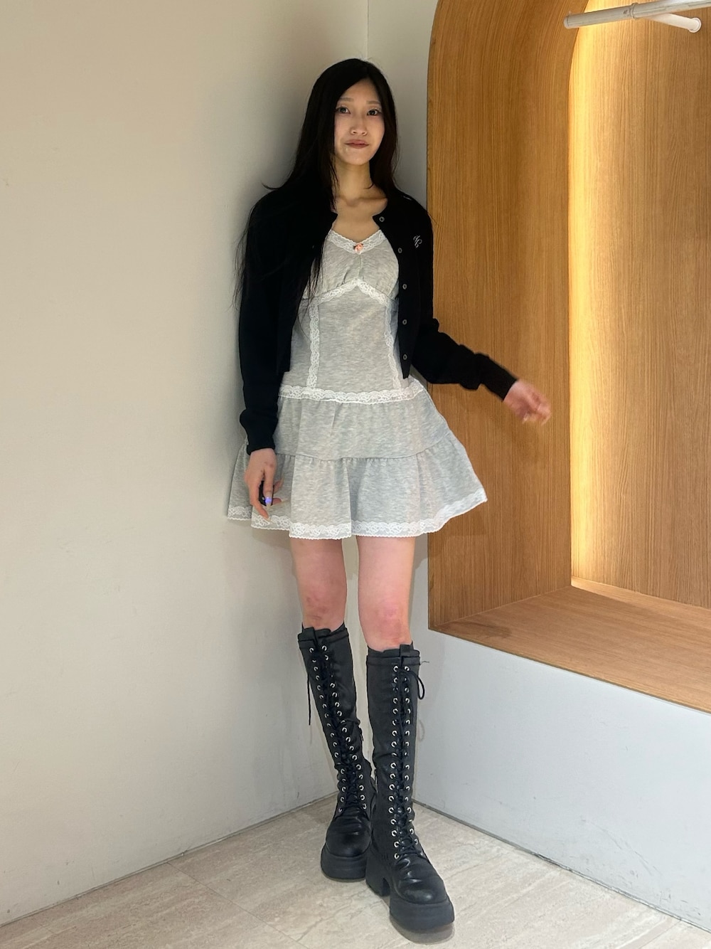 グレー系のワンピース、ブラック系のブーツ、ブラック系のカーディガン/ボレロを着用したレディースの春コーディネートの1枚目の写真