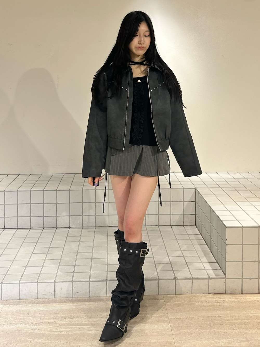 ブラック系のブーツ、グレー系のスカート、ブラック系のブルゾンを着用したレディースの冬コーディネートの1枚目の写真