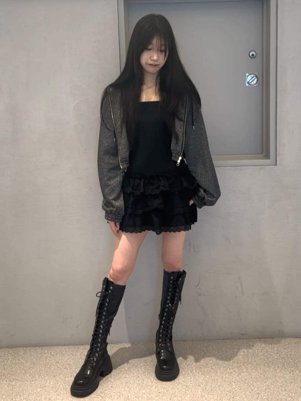 ブラック系のパーカー、ブラック系のワンピース、ブラック系のブーツを着用したレディースの春コーディネートの1枚目の写真