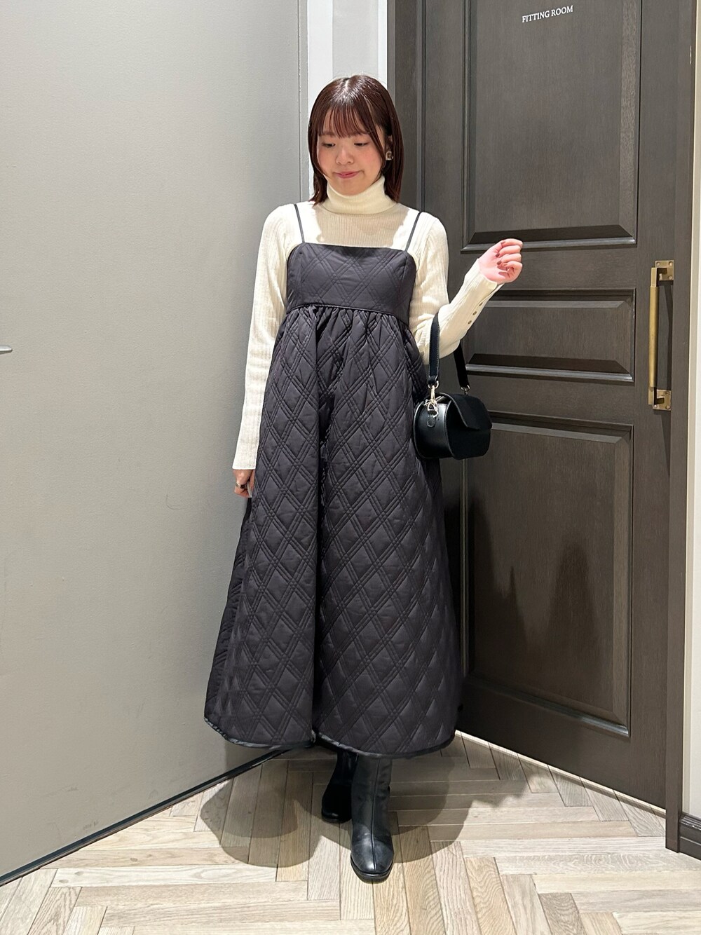 ブラック系のワンピース、ブラック系のブーツ、ホワイト系のニット/セーターを着用したレディースの秋コーディネートの1枚目の写真