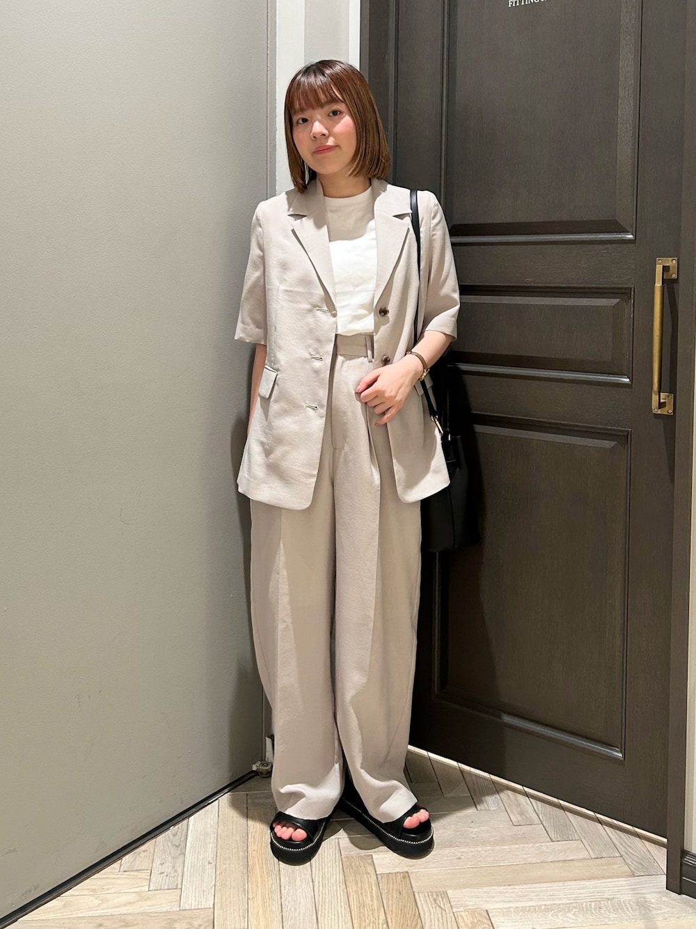 ベージュ系のその他パンツ、ブラック系のショルダーバッグ、ブラック系のサンダルを着用したレディースの夏コーディネートの1枚目の写真