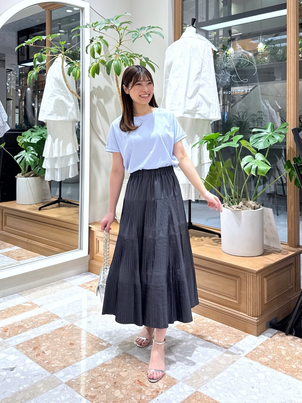 グレー系のスカート、シルバー系のハンドバッグ、ブルー系のTシャツ/カットソーを着用したレディースの春コーディネートの1枚目の写真