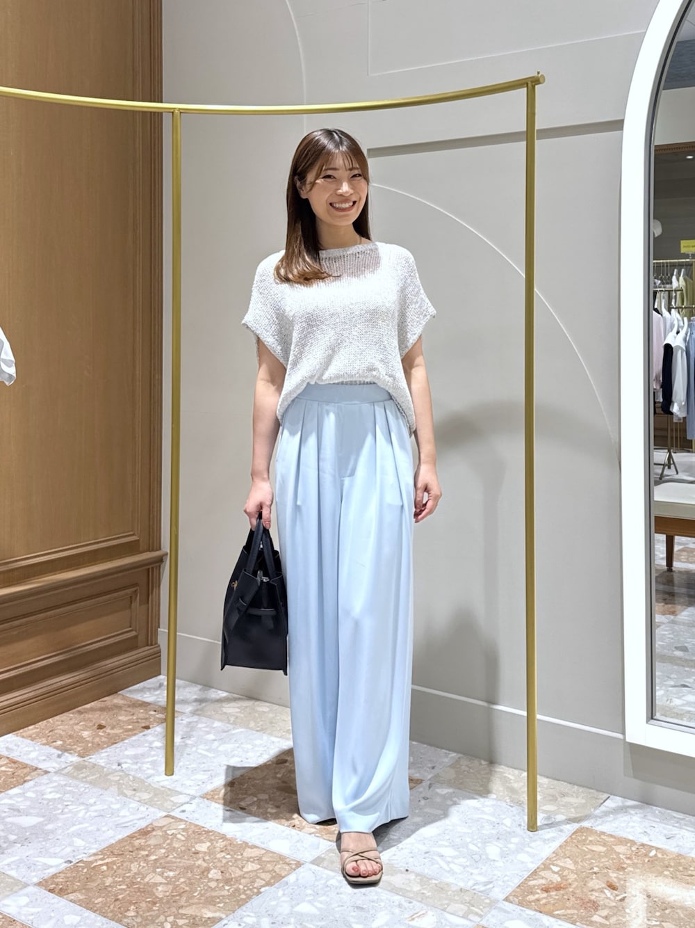 シルバー系のニット/セーター、ブルー系のスラックス、ブルー系のトートバッグを着用したレディースの夏コーディネートの1枚目の写真