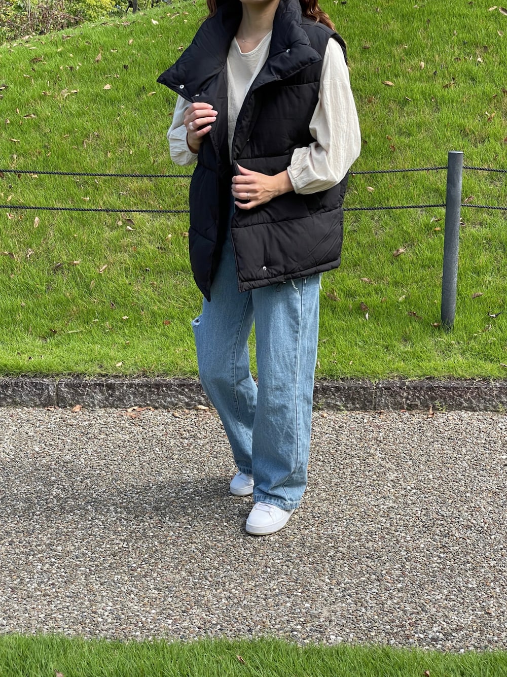 ブラック系のダウンベスト、ホワイト系のシャツ/ブラウス、ブルー系のデニムパンツを着用したレディースの秋コーディネートの1枚目の写真