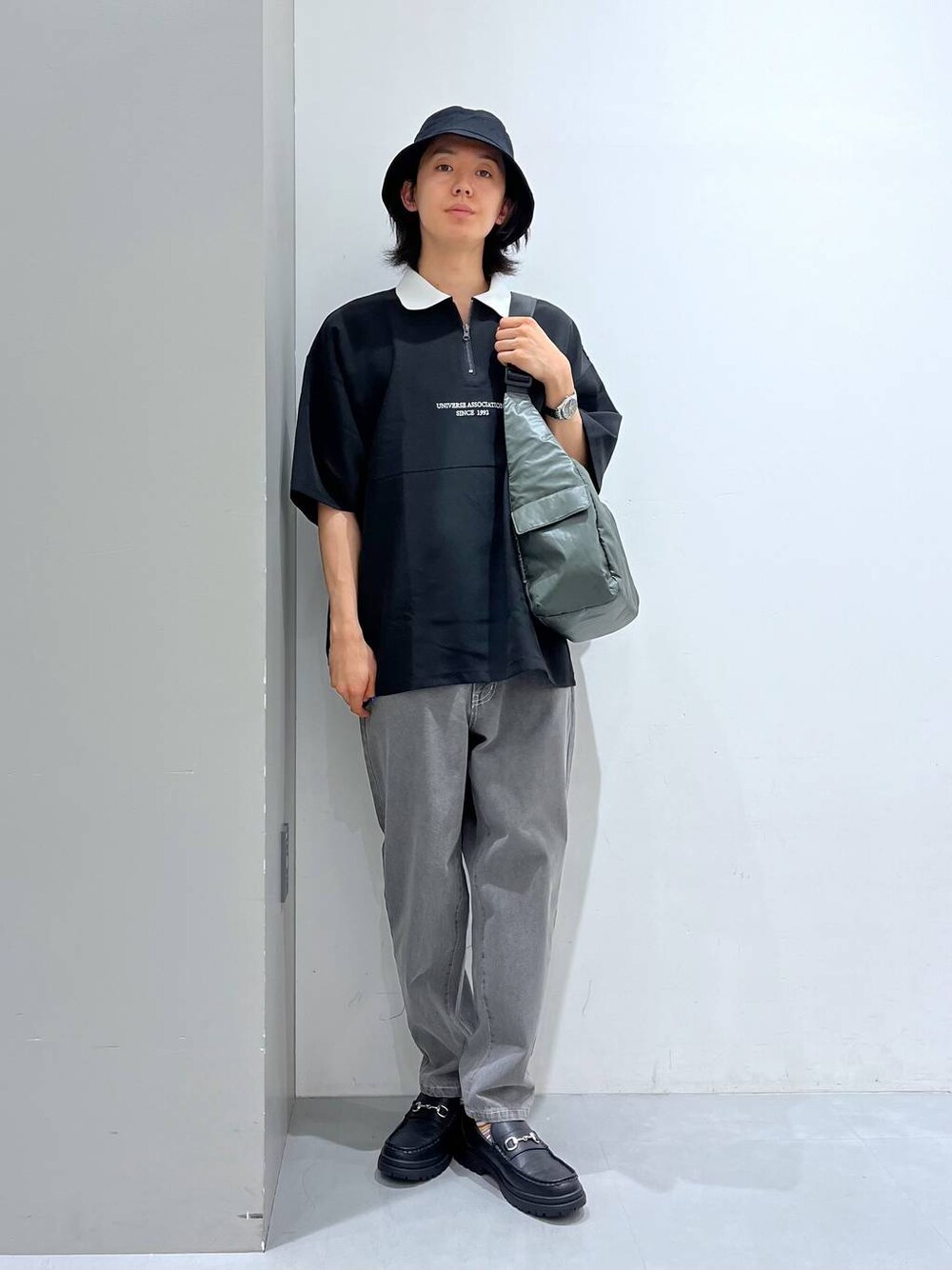 グリーン系のショルダーバッグ、ブラック系のローファー、ブラック系のシャツ/ブラウスを着用したメンズの夏コーディネートの1枚目の写真