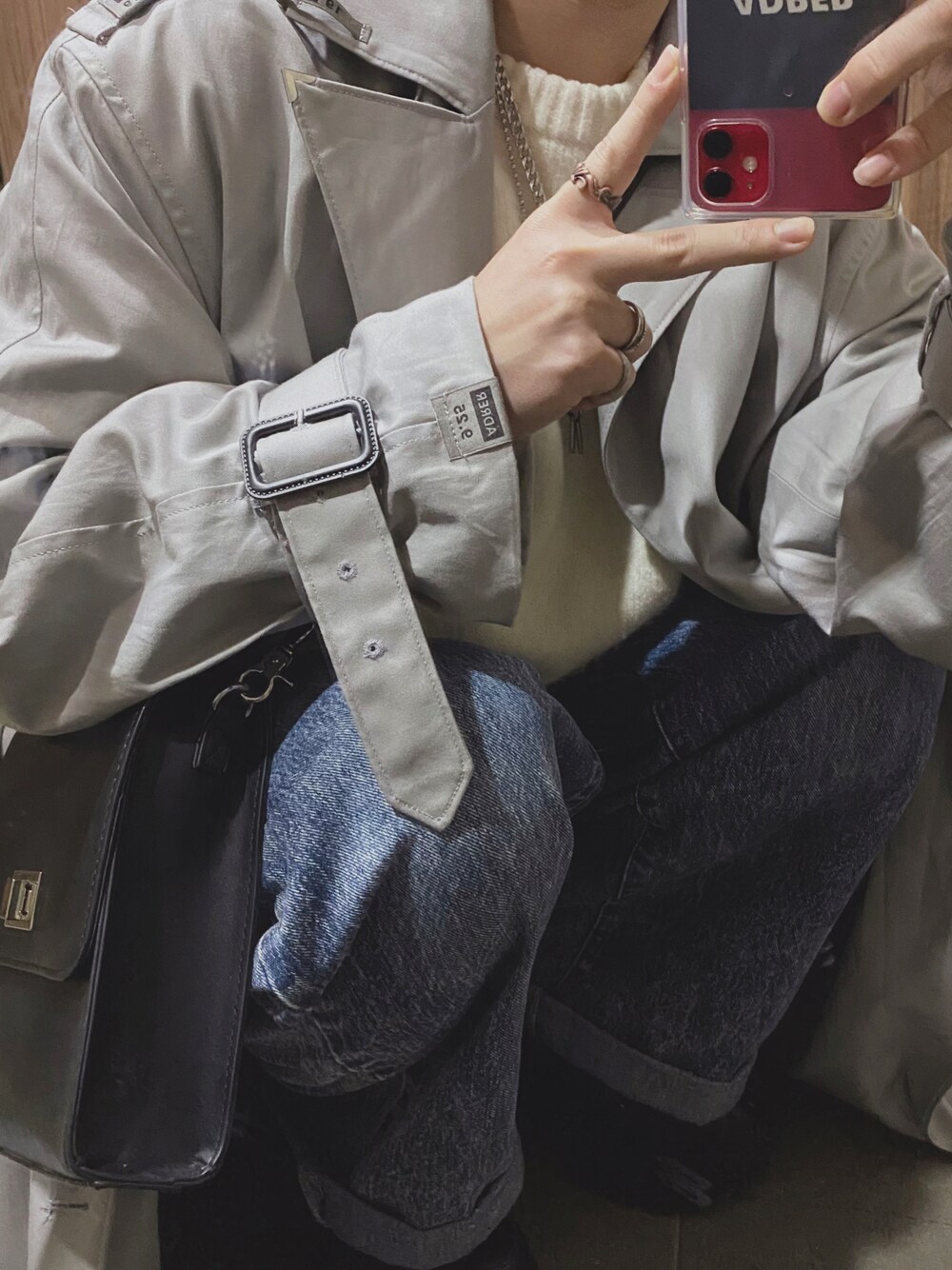 グレー系のトレンチコート、ホワイト系のニット/セーター、ブルー系のデニムパンツを着用したメンズの秋コーディネートの1枚目の写真