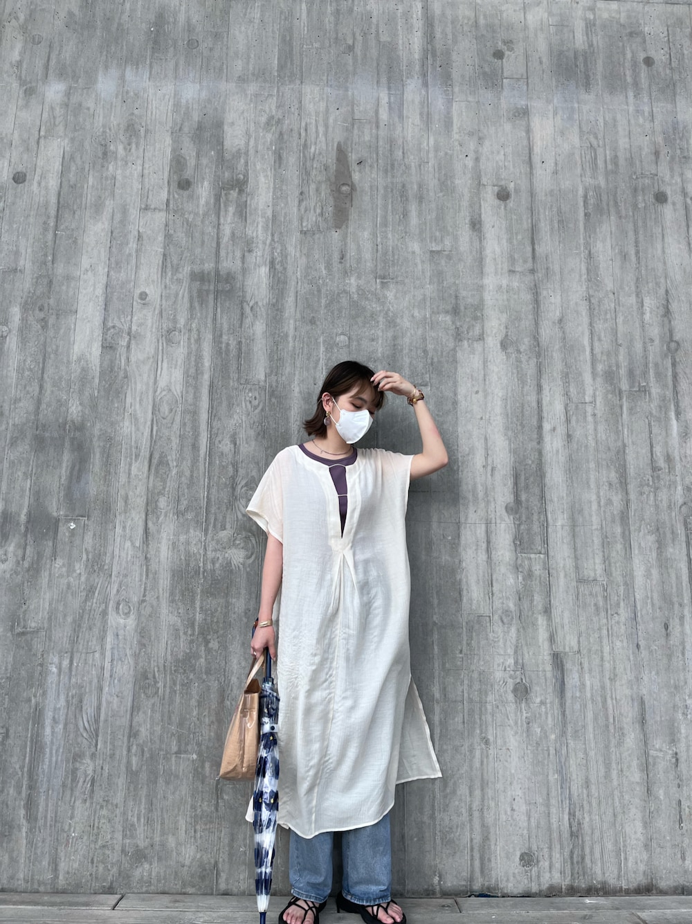 ホワイト系のシャツワンピース、ブラック系のサンダル、ブルー系の長傘を着用したレディースの夏コーディネートの1枚目の写真