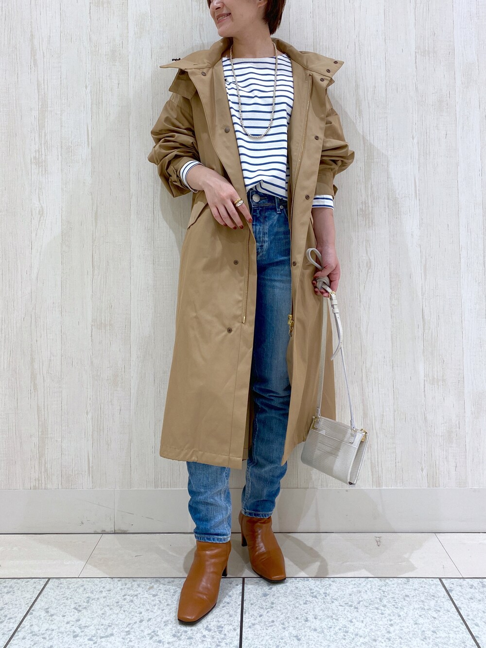 ベージュ系のモッズコート、ブルー系のデニムパンツ、ブルー系のTシャツ/カットソーを着用したレディースの秋コーディネートの1枚目の写真