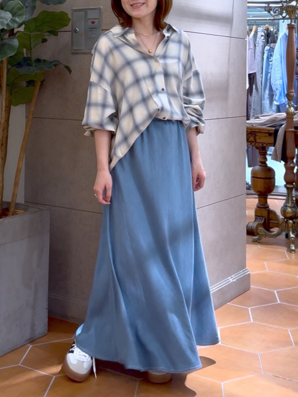 ブルー系のスカート、ベージュ系のシャツ/ブラウス、ゴールド系のネックレスを着用したレディースの夏コーディネートの1枚目の写真