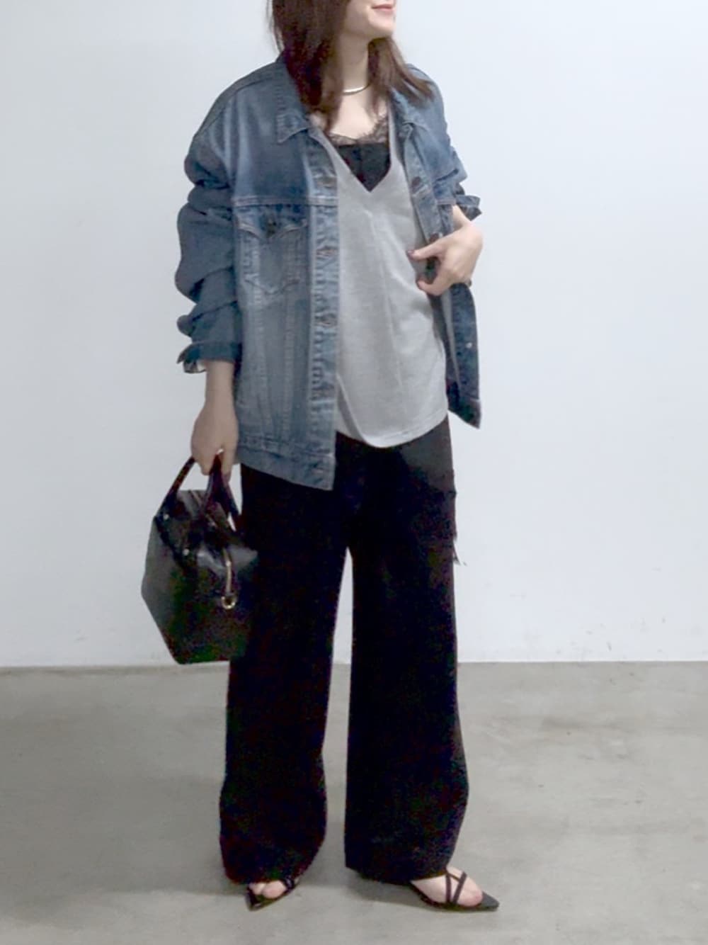 ブラック系のニット/セーター、グレー系のスウェット、ブルー系のデニムジャケットを着用したレディースの春コーディネートの1枚目の写真