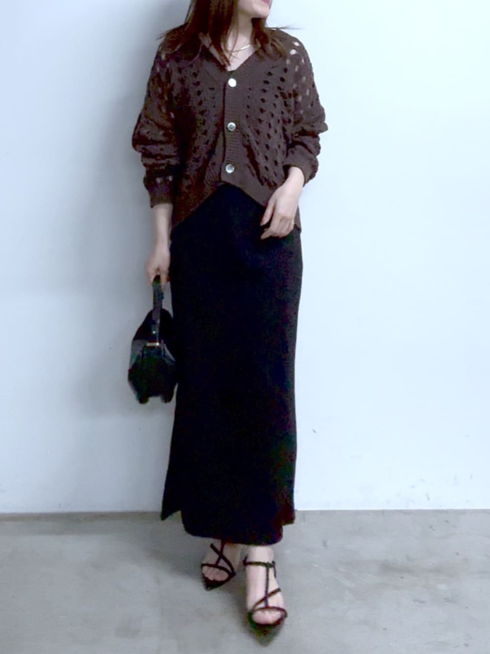 ブラウン系のカーディガン/ボレロ、ブラック系のワンピース、ブラック系のサンダルを着用したレディースの春コーディネートの1枚目の写真