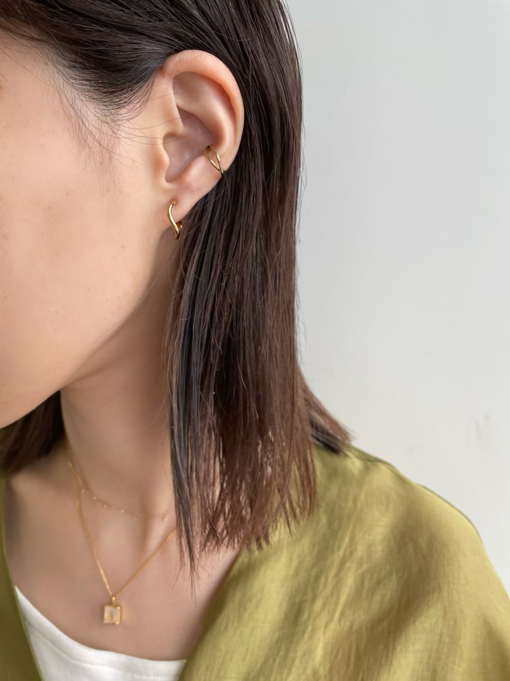 ゴールド系のイヤリング、ゴールド系のイヤーカフを着用したレディースの春コーディネートの1枚目の写真