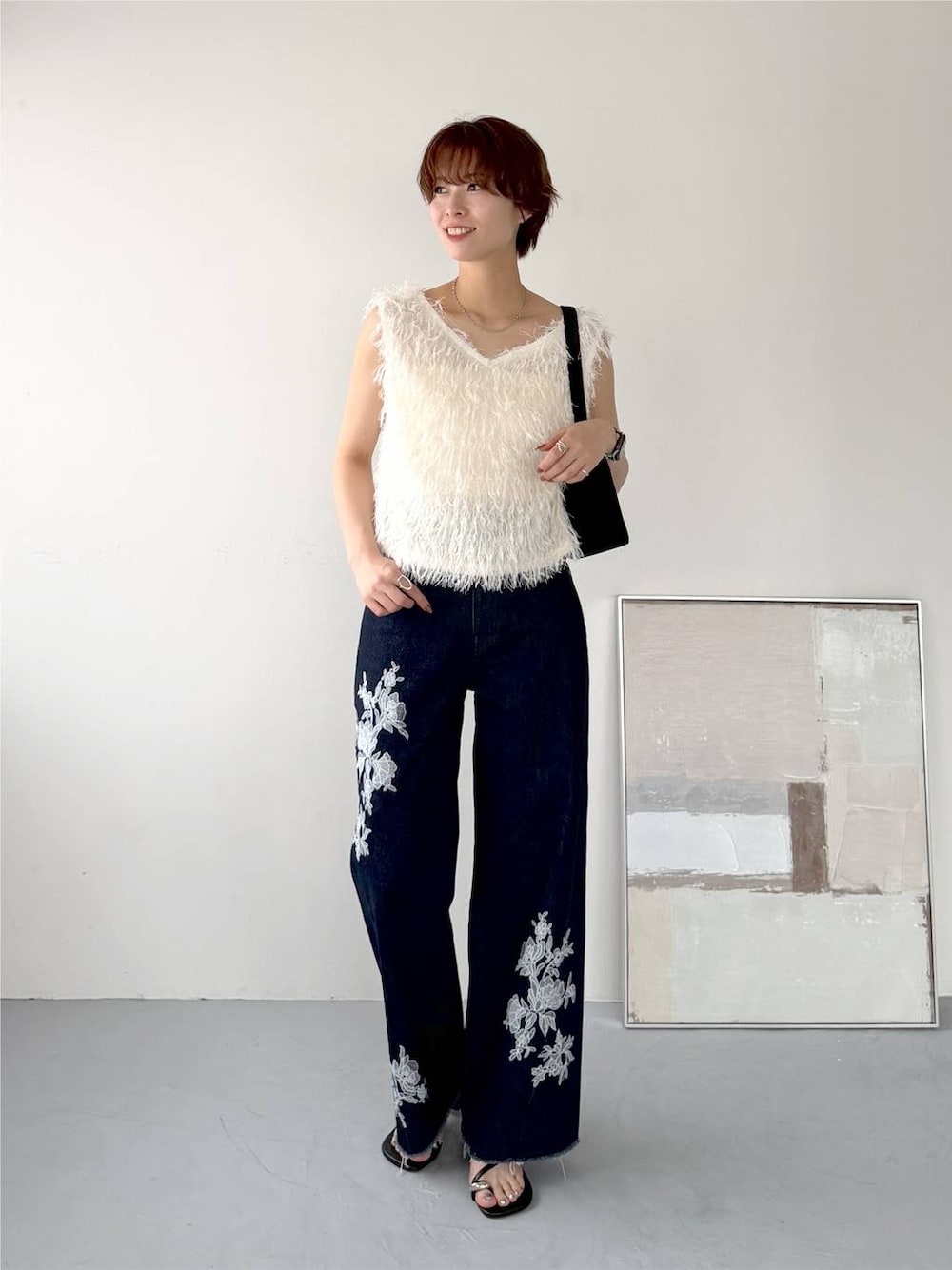 ホワイト系のベスト、ブルー系のデニムパンツ、ブラック系のサンダルを着用したレディースの夏コーディネートの1枚目の写真