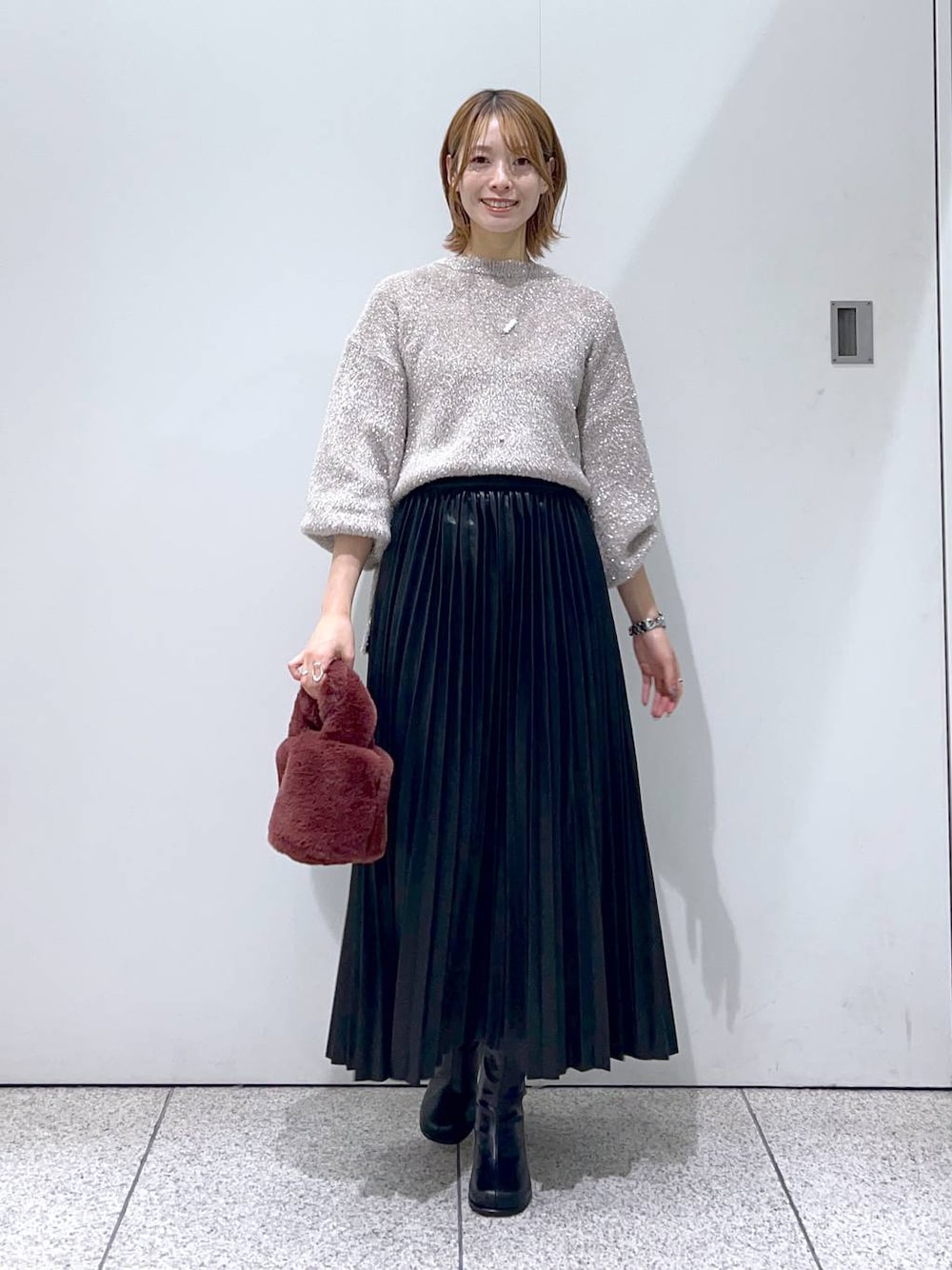 ブラック系のブーツ、ブラック系のスカート、ピンク系のハンドバッグを着用したレディースの秋コーディネートの1枚目の写真