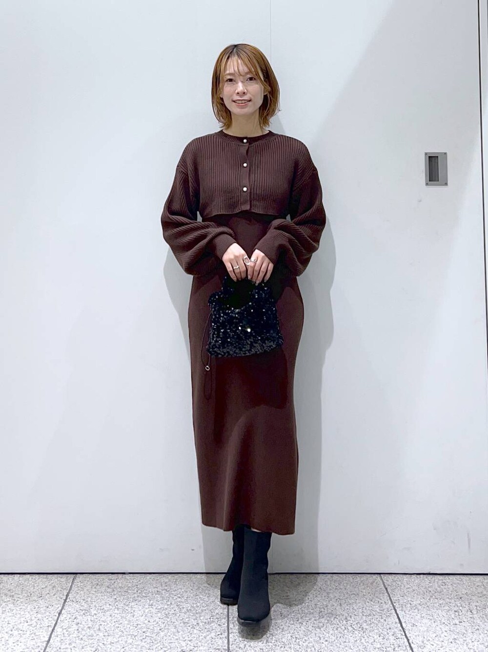 ブラック系のブーツ、ブラック系のハンドバッグ、ブラウン系のワンピースを着用したレディースの秋コーディネートの1枚目の写真