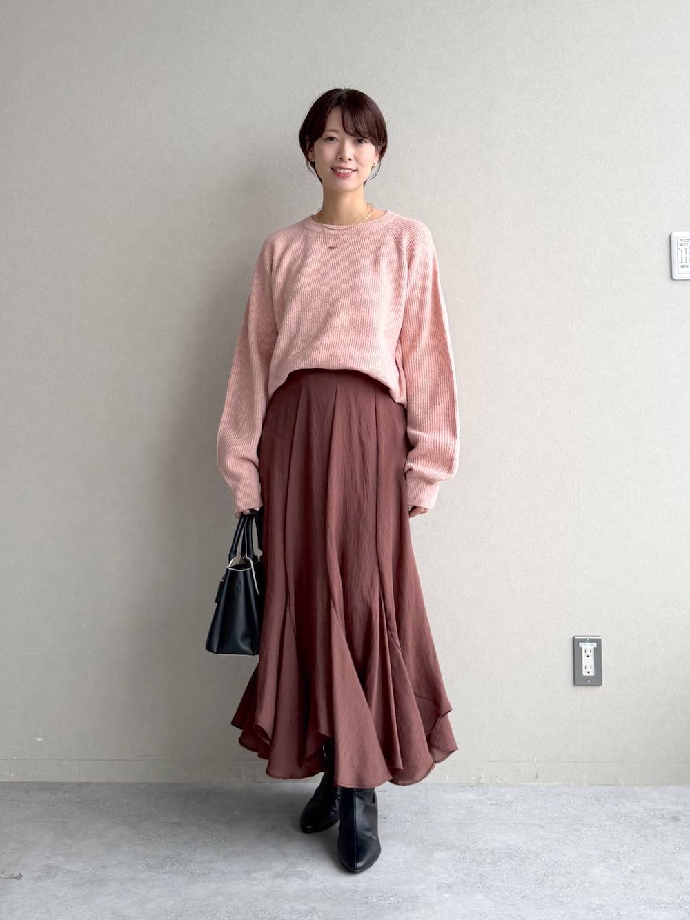 ピンク系のニット/セーター、ブラック系のショルダーバッグ、ブラウン系のスカートを着用したレディースの秋コーディネートの1枚目の写真