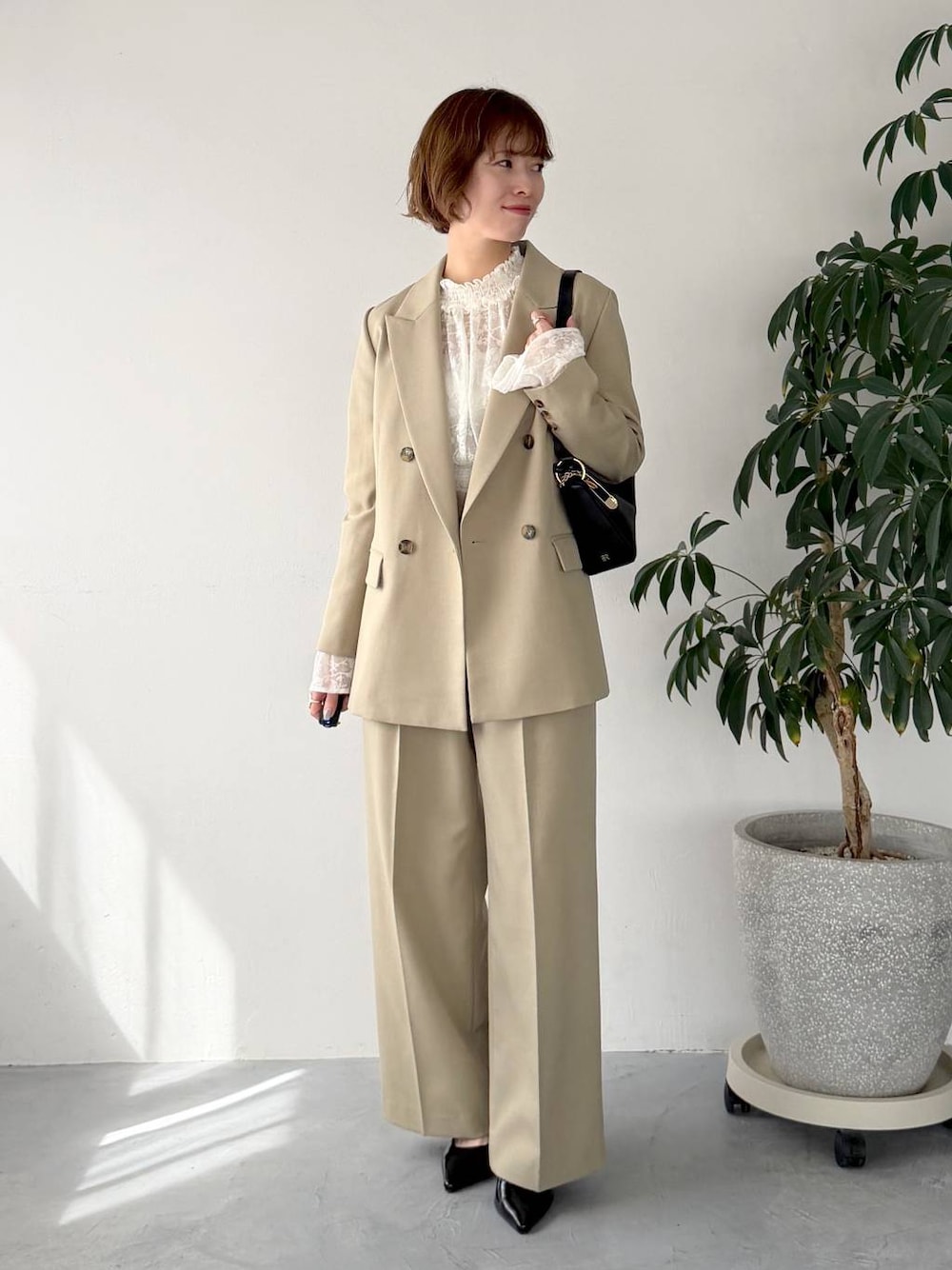 ベージュ系のテーラードジャケット、ベージュ系のその他パンツ、ブラック系のサンダルを着用したレディースの春コーディネートの1枚目の写真