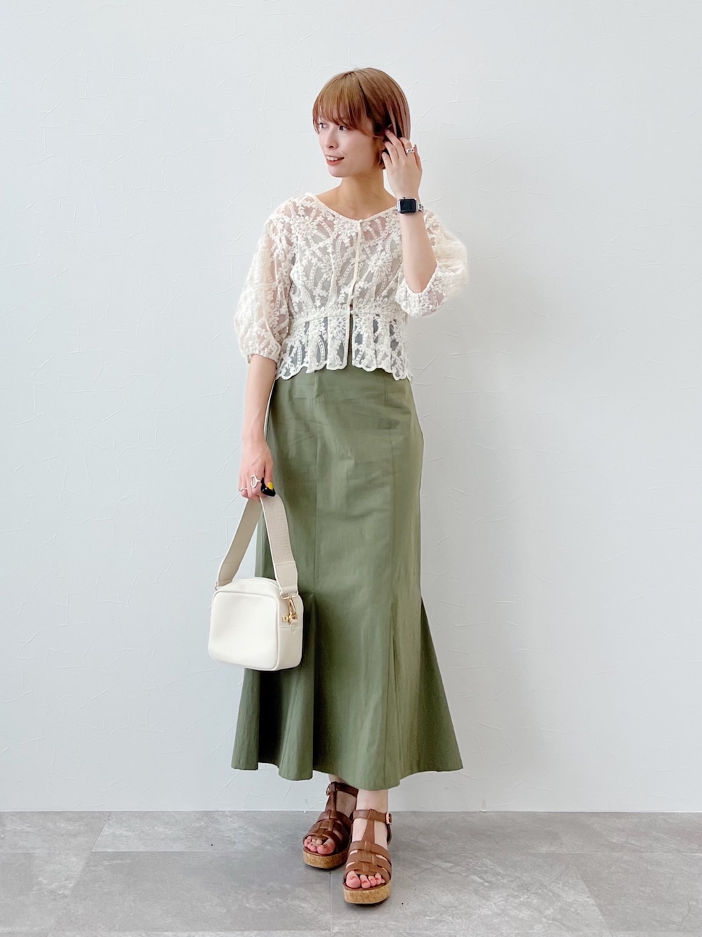 ホワイト系のシャツ/ブラウス、グリーン系のスカート、イエロー系のサンダルを着用したレディースの春コーディネートの2枚目の写真