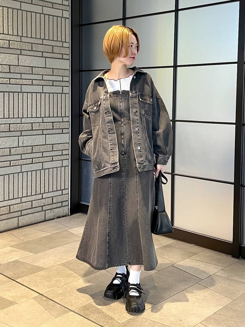 ブラック系のデニムジャケット、ブラック系のジャンパースカート、ブラック系のバレエシューズを着用したレディースの冬コーディネートの1枚目の写真