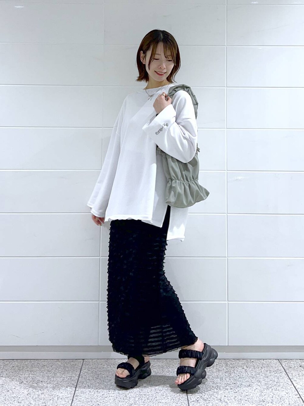 グリーン系のショルダーバッグ、ホワイト系のスウェット、ブラック系のサンダルを着用したレディースの春コーディネートの1枚目の写真