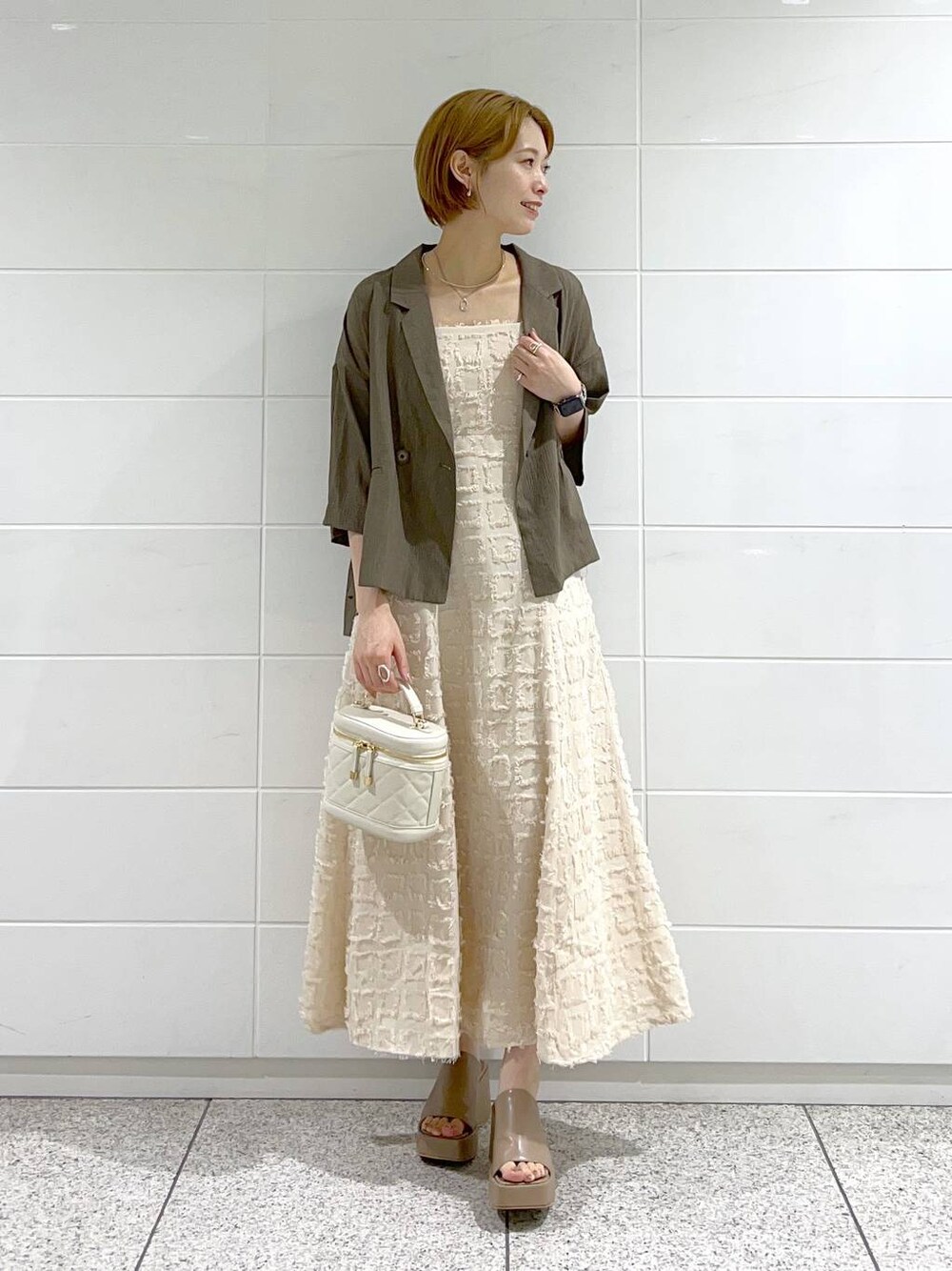 ベージュ系のサンダル、ホワイト系のショルダーバッグ、ベージュ系のワンピースを着用したレディースの夏コーディネートの1枚目の写真
