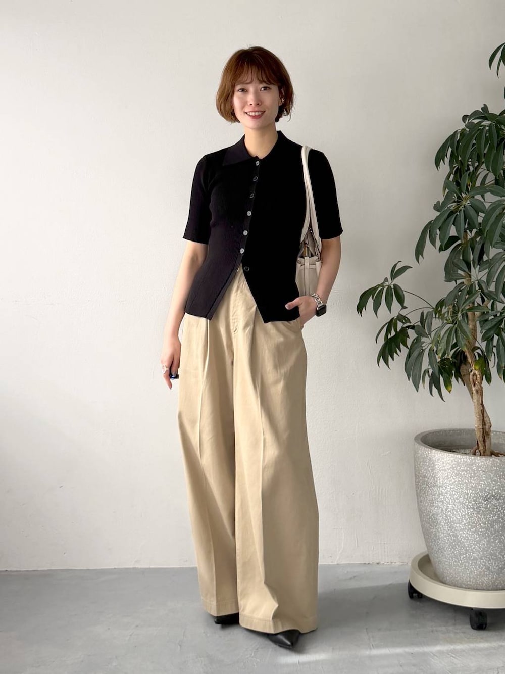 ブラック系のカーディガン/ボレロ、ベージュ系のチノパンツ、ホワイト系のショルダーバッグを着用したレディースの春コーディネートの1枚目の写真