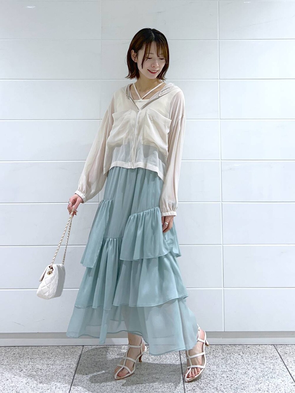 グリーン系のスカート、ホワイト系のショルダーバッグ、ホワイト系のパーカーを着用したレディースの春コーディネートの1枚目の写真